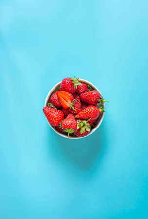 Fresh organic and juicy strawberries in pot on light blue backgroundの写真素材