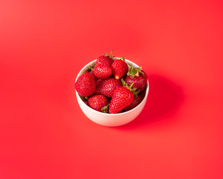 Fresh organic and juicy strawberries in pot on red backgroundの写真素材