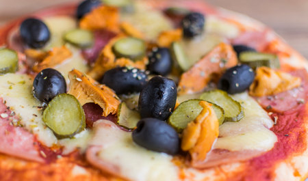 full frame photo of pizza made of olives, ham, cheese , cucumbers, mushrooms. Selective focusの写真素材
