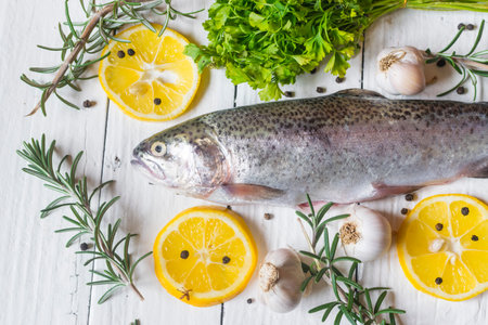 Fresh trout on old white table with parsley , garlic and rosemary. Tasty fish prepare for eating....