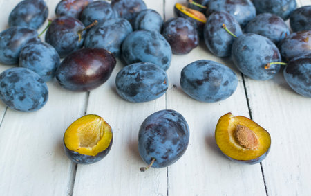 Fresh and ripped delicious plums on old white wooden table.の写真素材