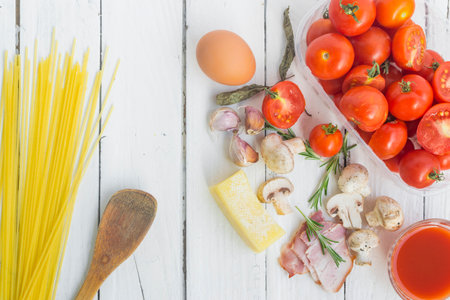 Frame with spaghetti and various ingredients for cooking pasta on a white background, top view.の写真素材