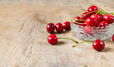 Fresh, red cherries in glass plate on old wooden backgroundの写真素材