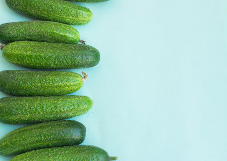 Fresh cucumbers on light blue background with place for text