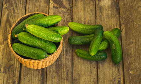 Fresh cucumbers in box and on old wooden table. Top viewの写真素材