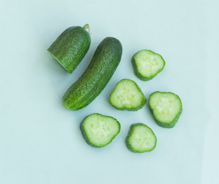 Fresh and sliced cucumbers on light blue background.の写真素材