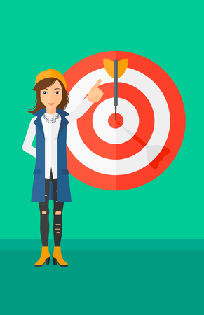 A woman pointing at arrow in a target board on a green background vector flat design illustration. Vertical layout.のイラスト素材