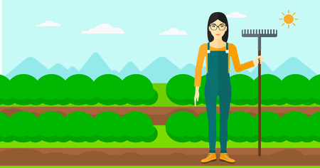 An asian woman standing with a rake on the background of field rows with green bushes vector flat design illustration. Horizontal layout.のイラスト素材
