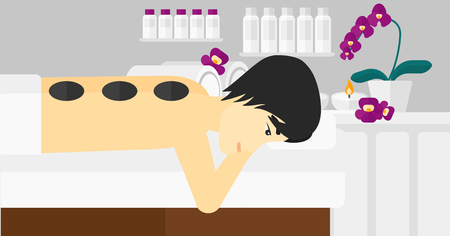 An asian man relaxing while getting stone therapy massage on the background of spa center vector flat design illustration. Horizontal layout.のイラスト素材
