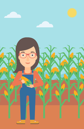 A woman with holding a corn cob on the background of field vector flat design illustration. Vertical layout.のイラスト素材