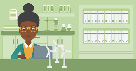 An african-american woman sitting at the table with a laptop and wind turbine models vector flat design illustration. Horizontal layout.のイラスト素材