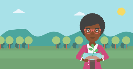 An african-american woman standing on the background of mountain landscape and holding in hands a plastic bottle with a small plant growing inside vector flat design illustration. Horizontal layout.のイラスト素材
