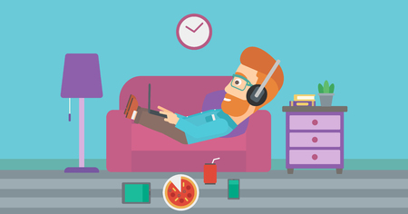 A hipster man in headphones lying on a sofa in living room with electronic devices and fast food vector flat design illustration. Horizontal layout.のイラスト素材