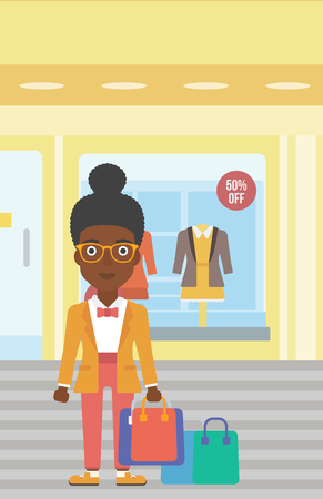 African-american woman holding shopping bags on the background of boutique window with dressed mannequins. Happy young woman carrying shopping bags. Vector flat design illustration. Vertical layout.のイラスト素材