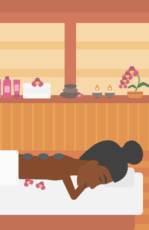 An african-american woman relaxing while getting stone therapy massage in the spa center. Woman having back massage in the spa salon. Vector flat design illustration. Vertical layout.のイラスト素材