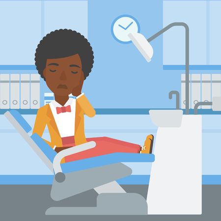 An african-american young female patient sitting in dental chair at dentist office and suffering from tooth pain. Woman having a toothache. Vector flat design illustration. Square layout.のイラスト素材