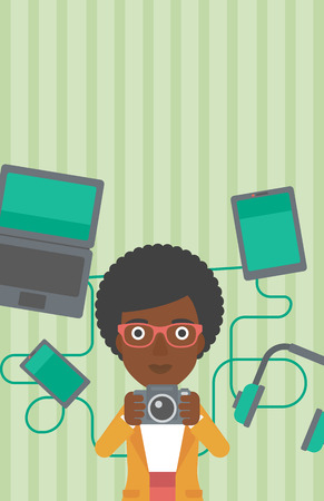 An african-american woman taking photo with digital camera. Woman surrounded with her electronic gadgets. Woman using many electronic gadgets. Vector flat design illustration. Vertical layout.のイラスト素材