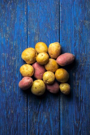 Starchy yellow and red potatoes on a blue wooden background, flat layの写真素材