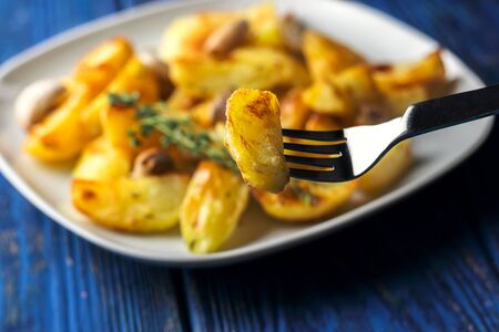 Crispy roasted potatoes with garlic and thyme on a blue wooden backgroundの写真素材