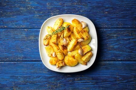 Crispy roasted potatoes with garlic and thyme on a blue wooden background, flat layの写真素材