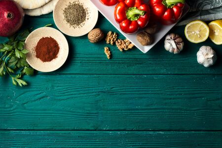 Various ingredients for Middle Eastern cuisine dish - muhammara - red bell pepper paste with walnuts on a dark green wooden backgroundの写真素材