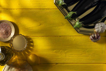 Various ingredients for mediterranean cuisine dish babaganoush on a yellow wooden backgroundの写真素材