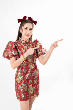 Happy Asian woman wearing traditional cheongsam qipao dress and hand gesture up pointing up to copy space isolated on White background. Happy Chinese new year Women with Happy Expression Conceptの写真素材