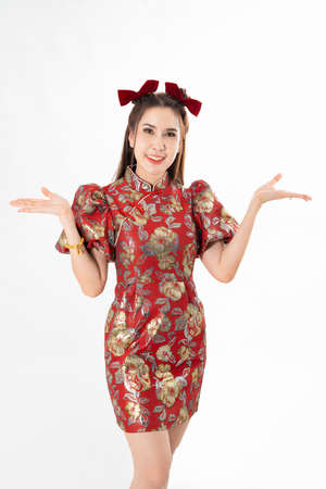 Happy Asian woman wearing traditional cheongsam qipao dress and hand gesture up pointing up to copy space isolated on White background. Happy Chinese new year Women with Happy Expression Conceptの写真素材