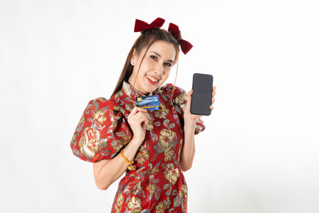 Happy chinese new year. excited young Woman showing blank smart phone screen, with credit card, mobile smart phone shopping online technology concept on white isolated backgroundの写真素材