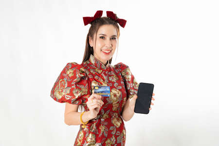 Happy chinese new year. excited young Woman showing blank smart phone screen, with credit card, mobile smart phone shopping online technology concept on white isolated backgroundの写真素材