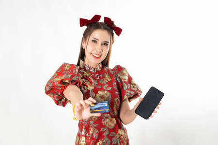 Happy chinese new year. excited young Woman showing blank smart phone screen, with credit card, mobile smart phone shopping online technology concept on white isolated backgroundの写真素材