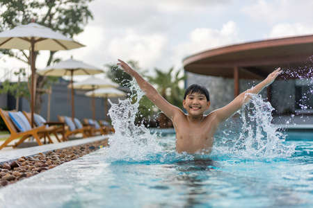 Asian Young Boy Having a good time in swimming pool, He Jumping and Playing a Water in Summer.の写真素材