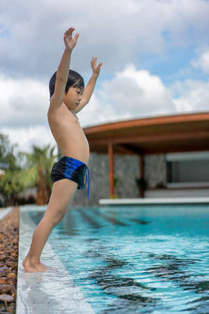 Asian Young Boy Having a good time in swimming pool, He Jumping and Playing a Water in Summer.の写真素材