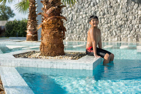 Asian Young Boy Having a good time in swimming pool, He Jumping and Playing a Water in Summer.の写真素材