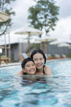 Asian Family, Young Boy Son and 40s Women Mother Having a Good Time Playing and Enjoying in Swimming Poolの写真素材