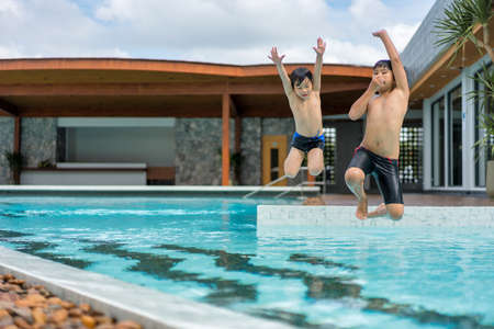 Asian Young Boy Brother Having a Good Time Playing and Enjoying in Swimming Pool Together in Summerの写真素材