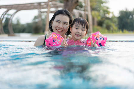 Asian Women Mom and Daughter Having a Good Time with Water in Swimming Pool Together in Summer day...