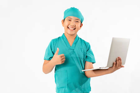 Portrait of Young Asian Boy Dressing to be Doctor, Holding Laptop Isolate on White Background, Education Conceptの写真素材