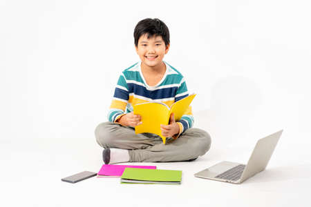 Portrait of Happy asian boy on floor with laptop and books isolated on white background, Education and learning with technology conceptの写真素材