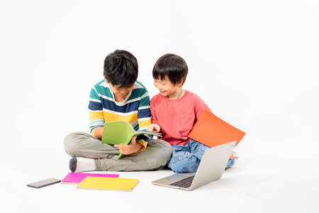 Portrait of Happy asian boys, Brother on floor with laptop and books isolated on white background, Education and learning with technology conceptの写真素材