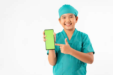 Portrait of Young Asian Boy Dressing to be Doctor, Holding Smart phone with Green Screen Isolate on...