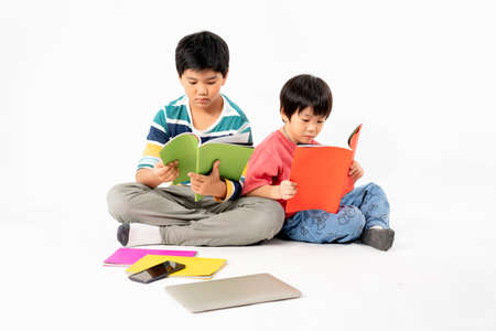 Portrait of Happy asian boys, Brother on floor with laptop and books isolated on white background, Education and learning with technology conceptの写真素材