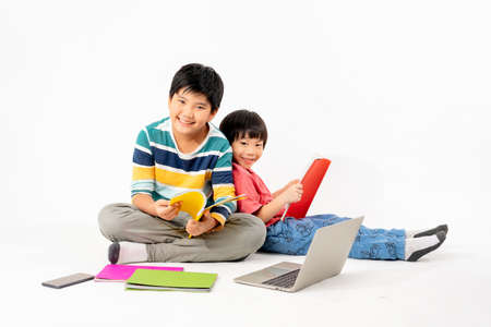 Portrait of Happy asian boys, Brother on floor with laptop and books isolated on white background, Education and learning with technology conceptの写真素材