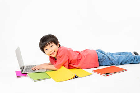 Portrait of Happy asian boy on floor with laptop and books isolated on white background, Education and learning with technology conceptの写真素材