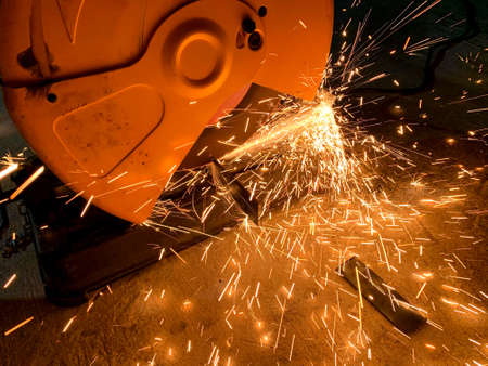 Professional mechanic is cutting steel metal with rotating diamond blade cutter. sparks while...