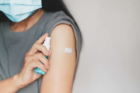 senior hand holding spray alcohol bottle, wearing medical face mask after vaccinated or inoculation ...