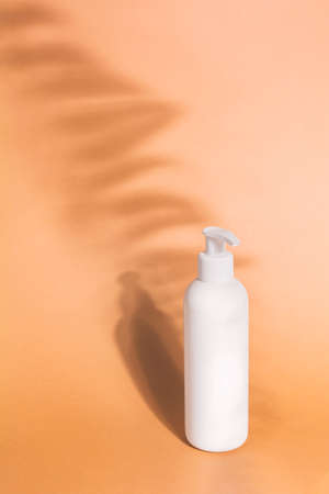 White pump plastic bottle mockup beige background with shadow fern leaves. Dispenser bottle, shampoo mock up. Branding, labels and packagingの写真素材