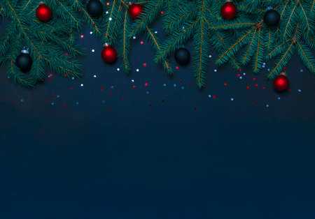 Christmas frame top border with fir tree branches, balls and confetti on dark blue background....
