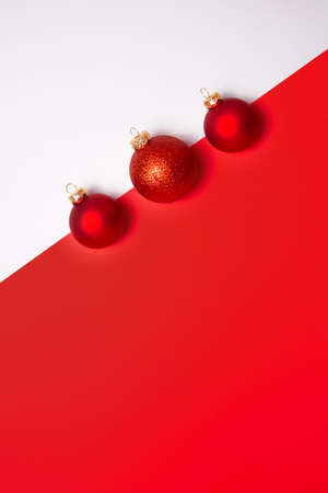 Minimal christmas postcerd with baubles decoration on white and red background. Holiday concept. Flat lay, top view with copy spaceの写真素材