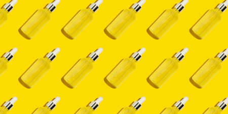 Glass serum bottle pattern on bright yellow background. Medicine or cosmetic pipette dropper mock up. Jars with organic essential. Flat lay, top viewの写真素材